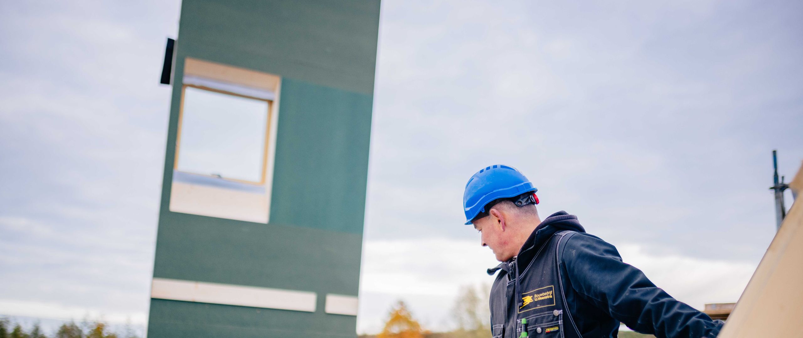 Medewerker van U. Veenstra plaatst geveldeel op de bouwplaats