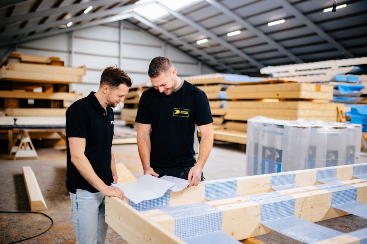 Twee medewerkers van U. Veenstra controleren werktekening in de prefabhal