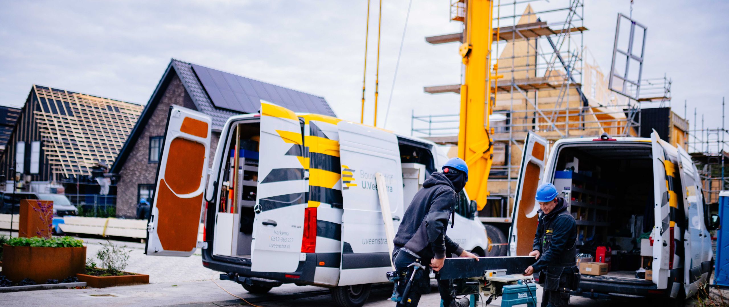 U. Veenstra medewerkers laden materiaal uit werkbussen op de bouwplaats