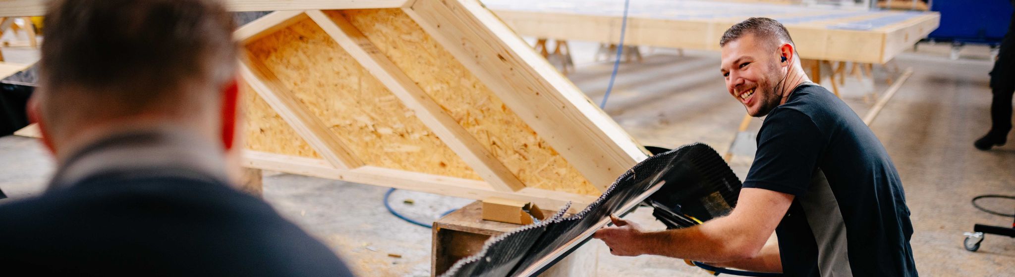 Medewerker van U. Veenstra werkt aan houten dakelement in de werkplaats.