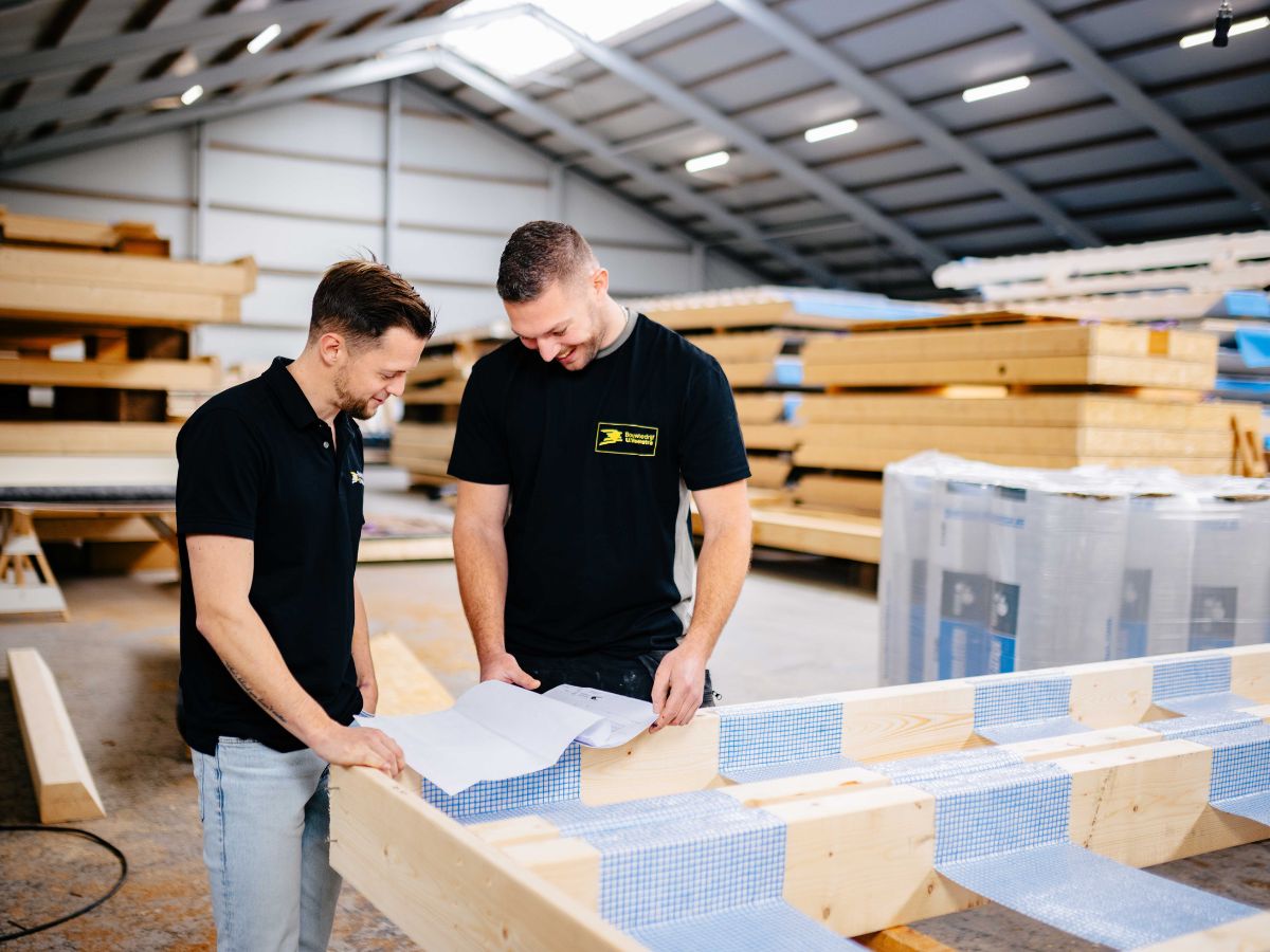 Twee collega\'s van Bouwbedrijf U. Veenstra bespreken tekeningen in de werkplaats