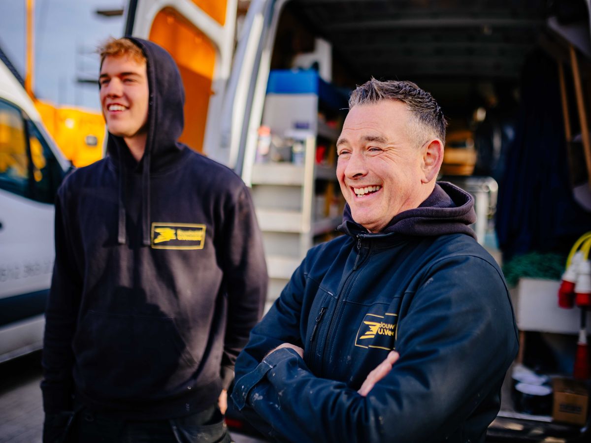 Twee personen in werkkleding naast een bestelbus