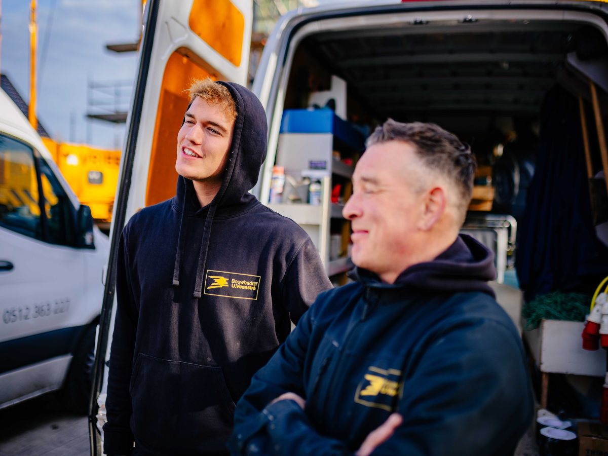 Twee werknemers praten voor de werkbus op de bouwplaats