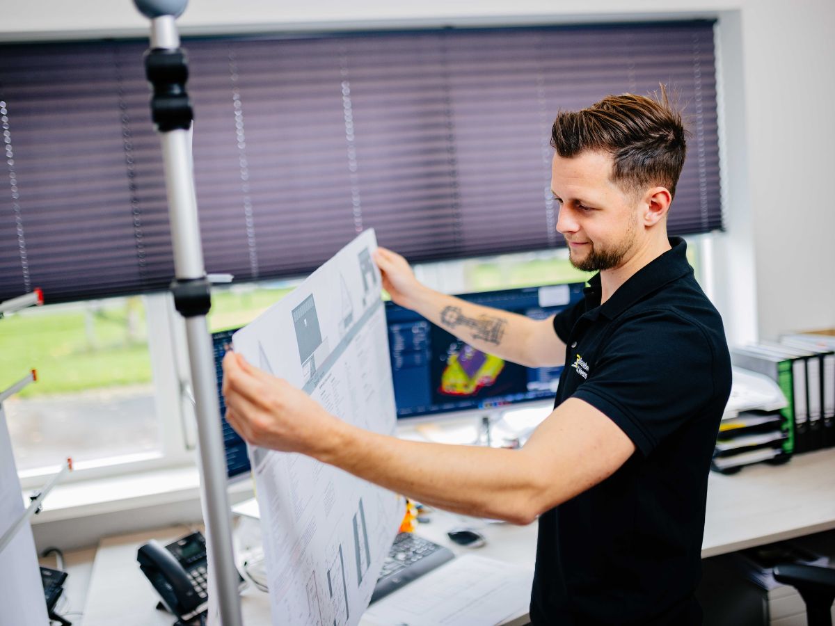 U. Veenstra werkvoorbereider bekijkt bouwtekening op kantoor.